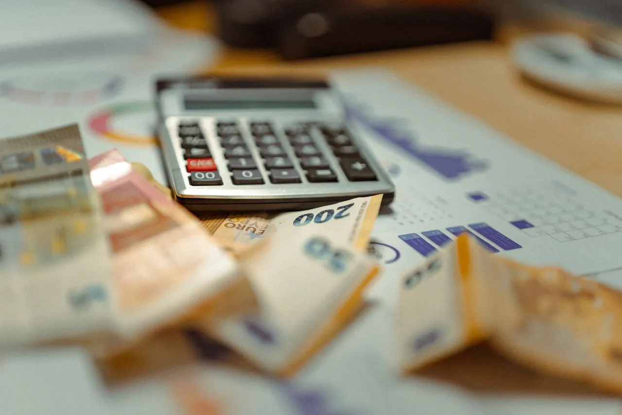 GmbH pleite was passiert — Taschenrechner und Euro-Geldscheine auf Finanzdokumenten